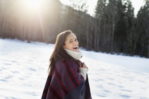 Portrait of smiling woman walking in snowy field