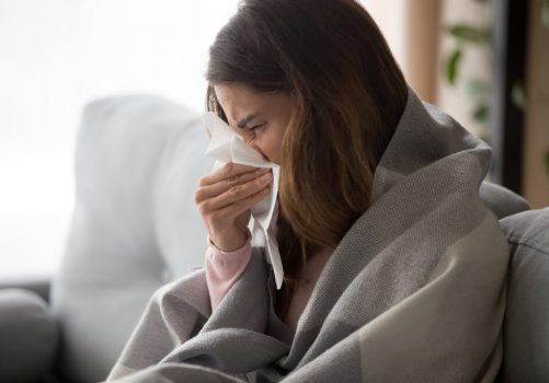 Ill,Upset,Young,Woman,Sitting,On,Sofa,Covered,With,Blanket