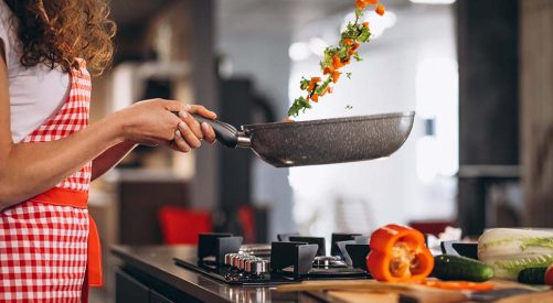 Woman chef cooking vegetables in pan